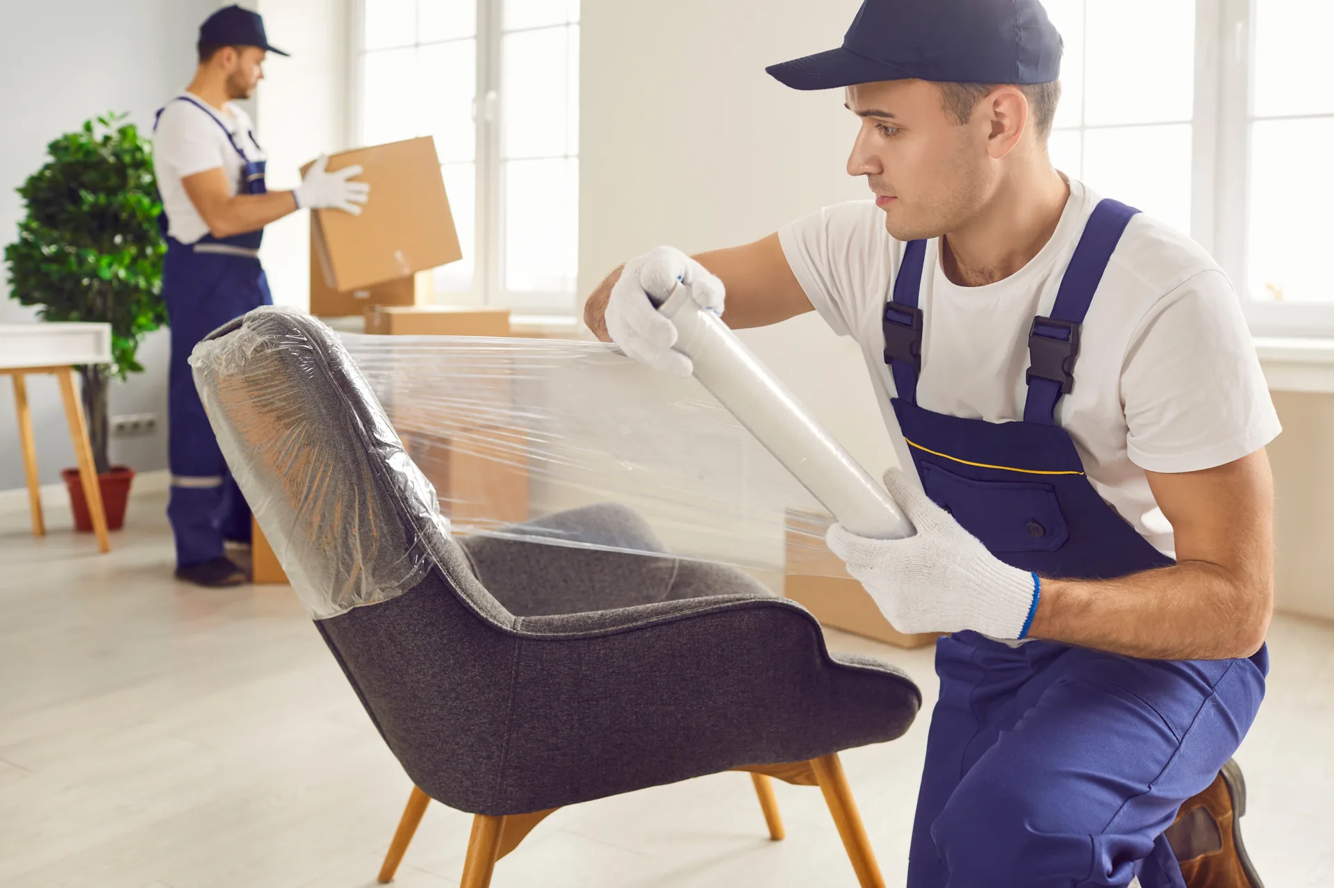 Möbelpacker verpackt einen Sessel sorgfältig in Schutzfolie